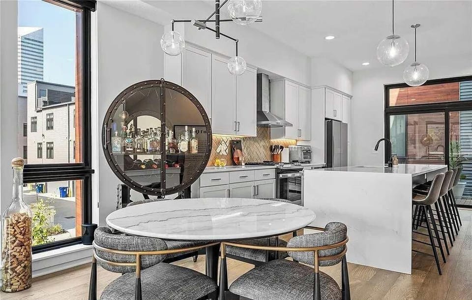 Modern kitchen with a marble dining table and a circular glass cabinet for drinks.