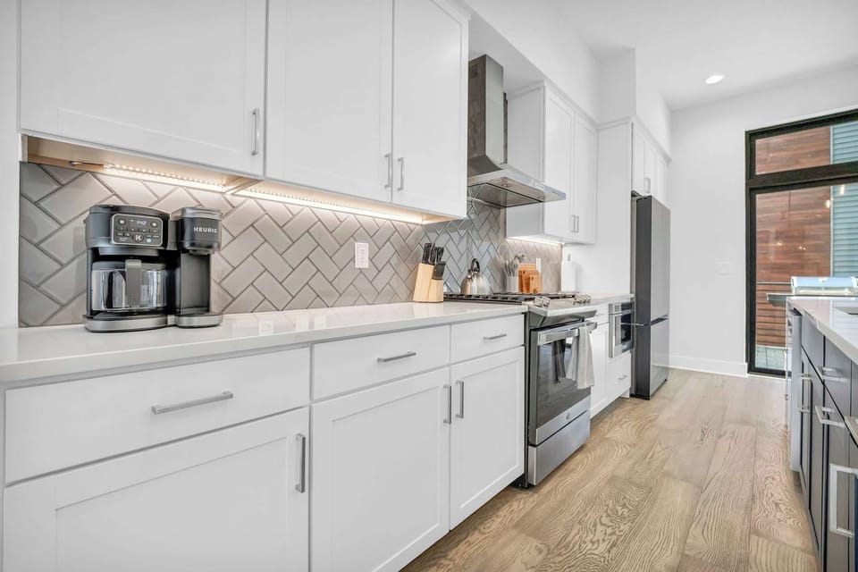 Modern kitchen with white cabinetry, stainless steel appliances, and a coffee maker on the counter.