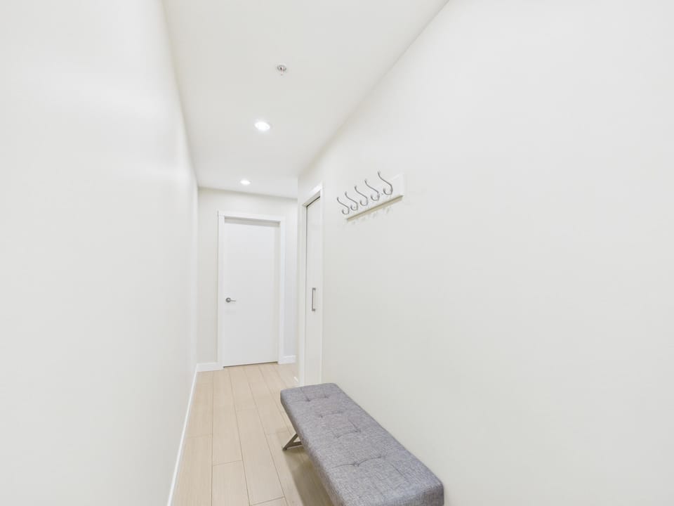 A long, welcoming entry hallway featuring clean lines, bright lighting, and a convenient bench.