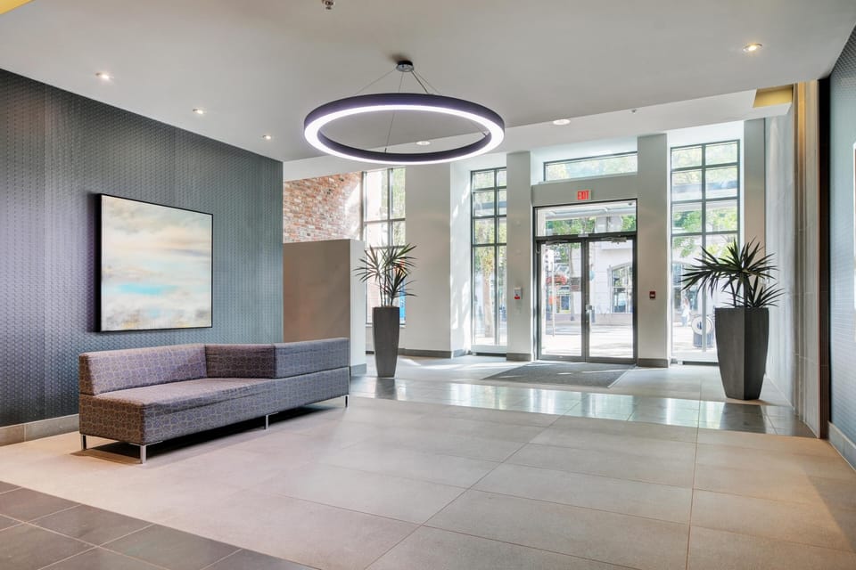 Welcome home! Walk through a secure, ultra-modern building lobby detailed with contemporary lighting.