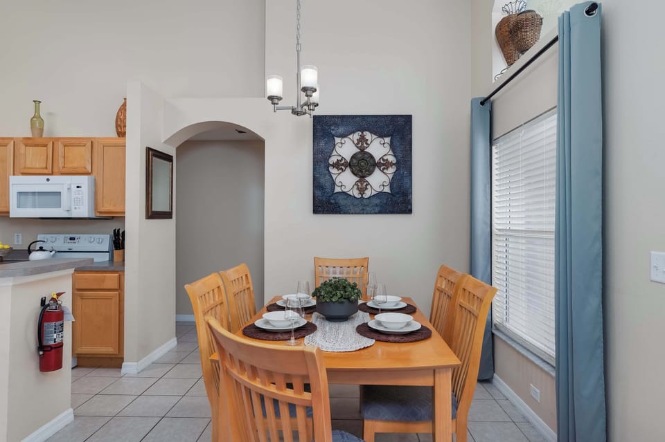 Cheerful dining area w/ wooden table, warmed by natural light.
