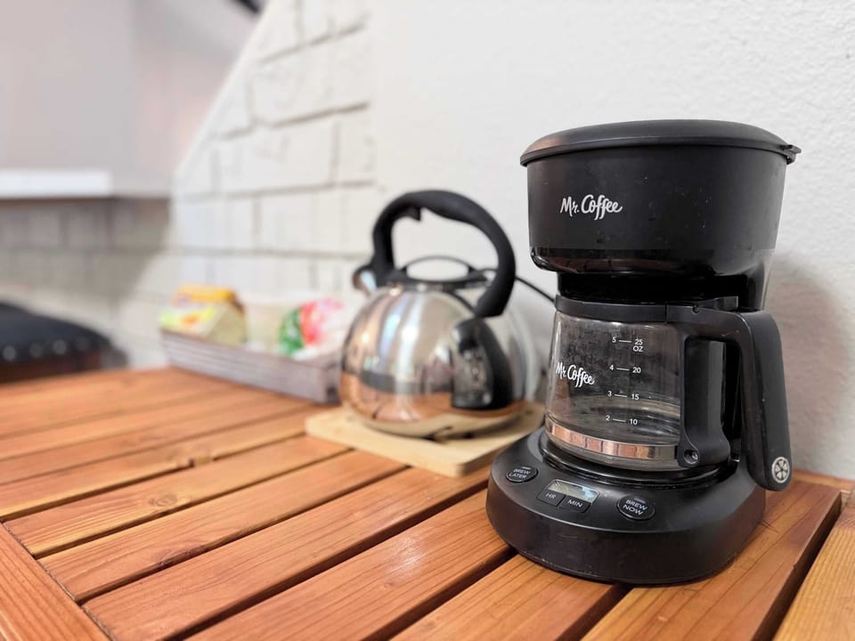 Kitchen counter with drip coffee maker and stainless kettle - first morning sorted before you've unpacked.
