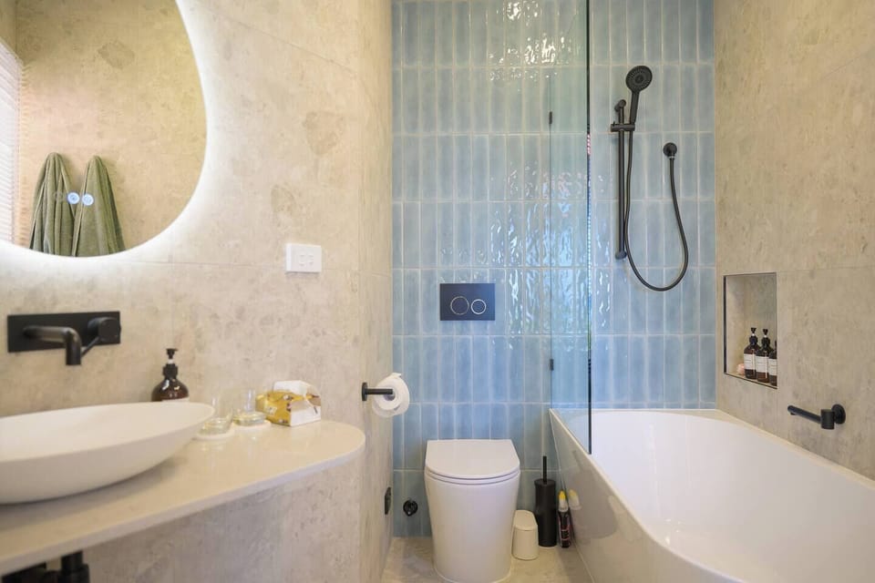 Indulge in the serene elegance of our bathroom, featuring a spacious tub, chic tiling, and rain shower. It's the perfect spa-like retreat to refresh and rejuvenate.