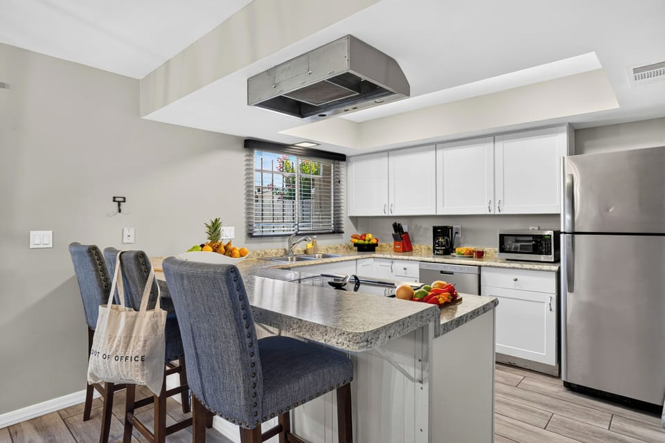 Bright kitchen with granite counters, stainless steel appliances, and breakfast bar seating.