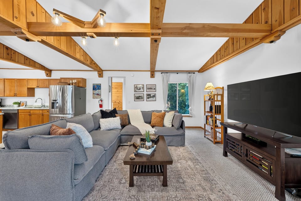 Relax in style in this expansive living room featuring oversized sectional seating and rich architectural wood beams.