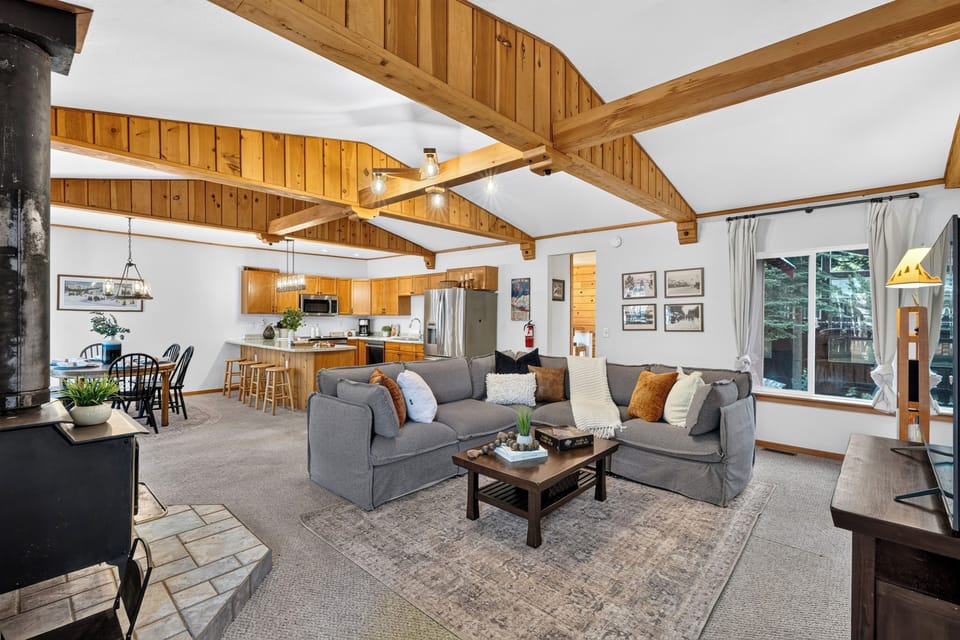 The spacious open-concept living area boasts beautiful vaulted wood ceilings, exposed beams, and comfortable seating for the whole family.