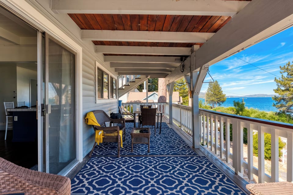 Covered lake-view balcony with lounge seating and breezy outdoor dining space.