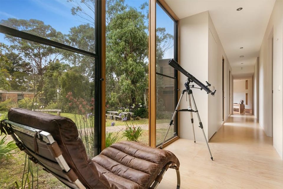 Sunlit hallway with garden views, lounge chair, and telescope nook
