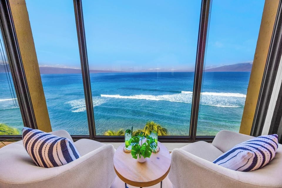 Two lounge chairs by the window invite slow afternoons, with Molokai on the horizon beyond the blue water. MAH-1006