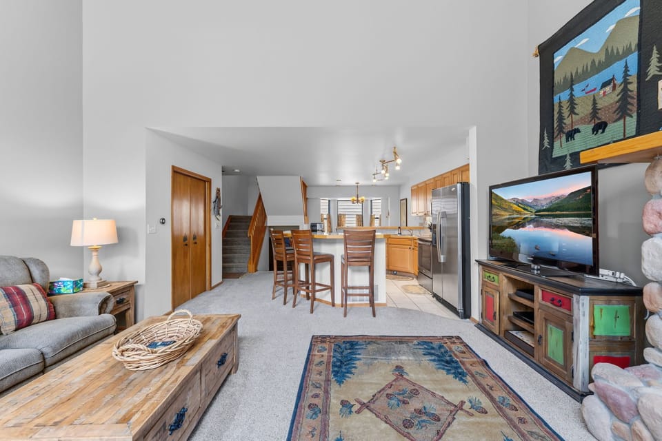 Relax in your open-concept living space with comfortable seating, warm wood accents, and mountain-inspired decor. The full kitchen invites you to prepare meals while enjoying views throughout.