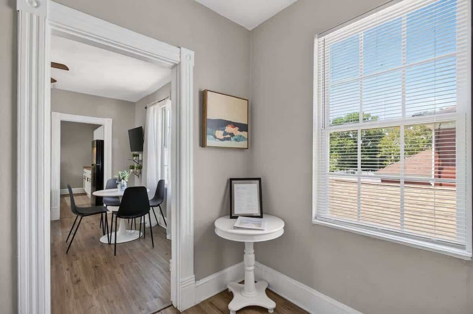 Bright corner nook with natural light, coastal artwork, and easy flow into the living and dining area.