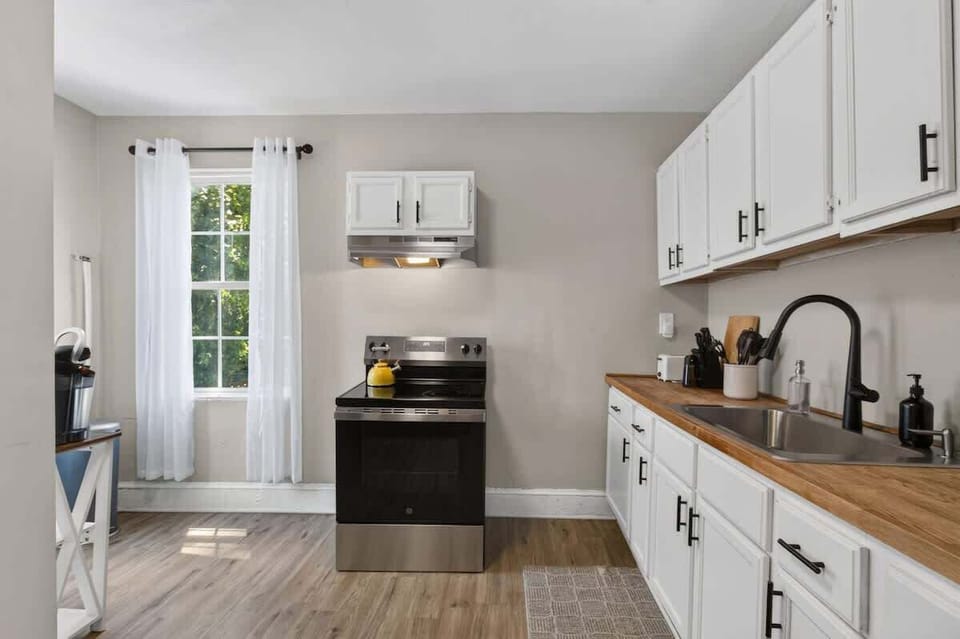 Bright and functional kitchen with white cabinetry, wood countertops, modern appliances, and natural light.
