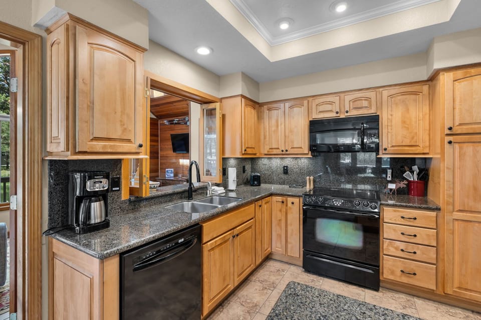 Your fully equipped kitchen features warm maple cabinetry, granite countertops, and modern appliances including a coffee maker and dishwasher—perfect for preparing delicious home-cooked meals during your stay.