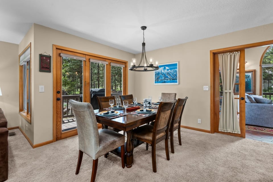 Gather around this inviting dining table set for six, where you'll enjoy meals together with natural light streaming through French doors leading to your private deck and forested views.