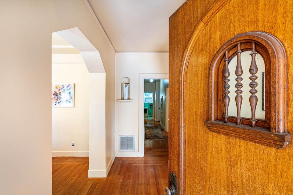 Step through the charming arched doorway into your cozy retreat, where warm wood floors and bright, open spaces welcome you home after a day of exploring.