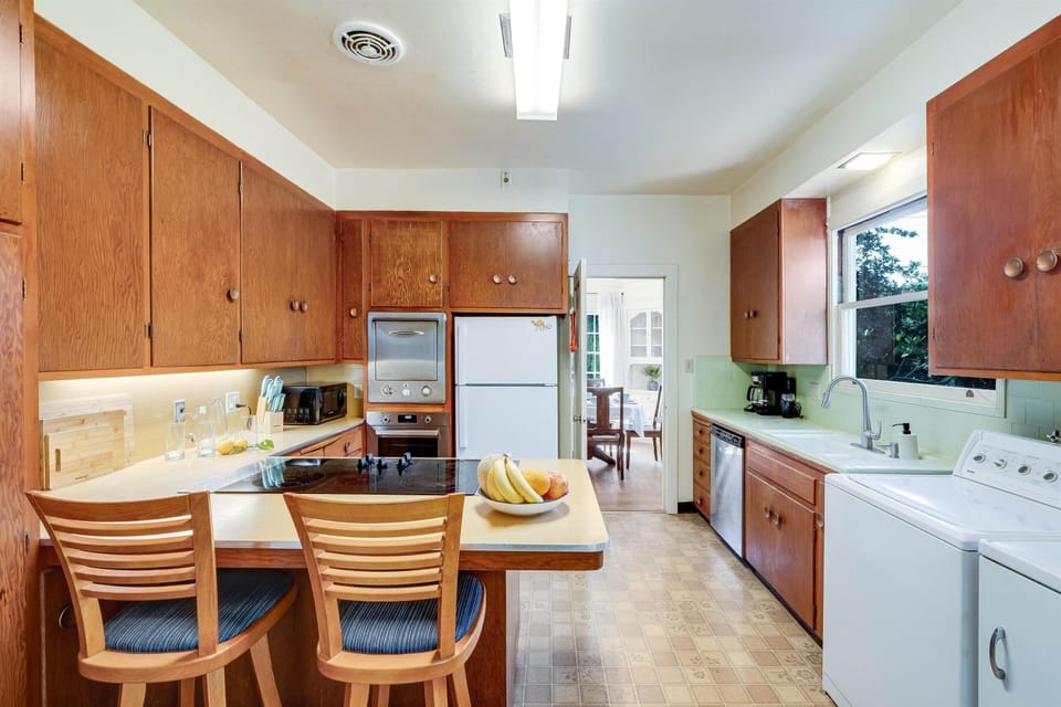 Your bright galley kitchen features warm oak cabinetry, full appliances, and a breakfast bar where you can enjoy fresh fruit and coffee each morning.