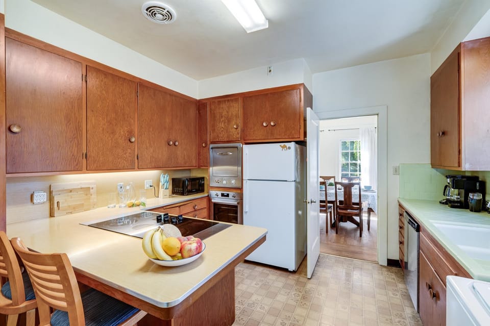 Your fully equipped kitchen offers plenty of counter space, warm wood cabinetry, modern appliances, and natural light—perfect for preparing meals at your leisure during your stay.