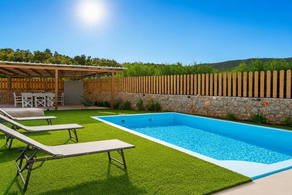 Sunny private pool area with sun loungers, shaded outdoor dining, and peaceful green surroundings.