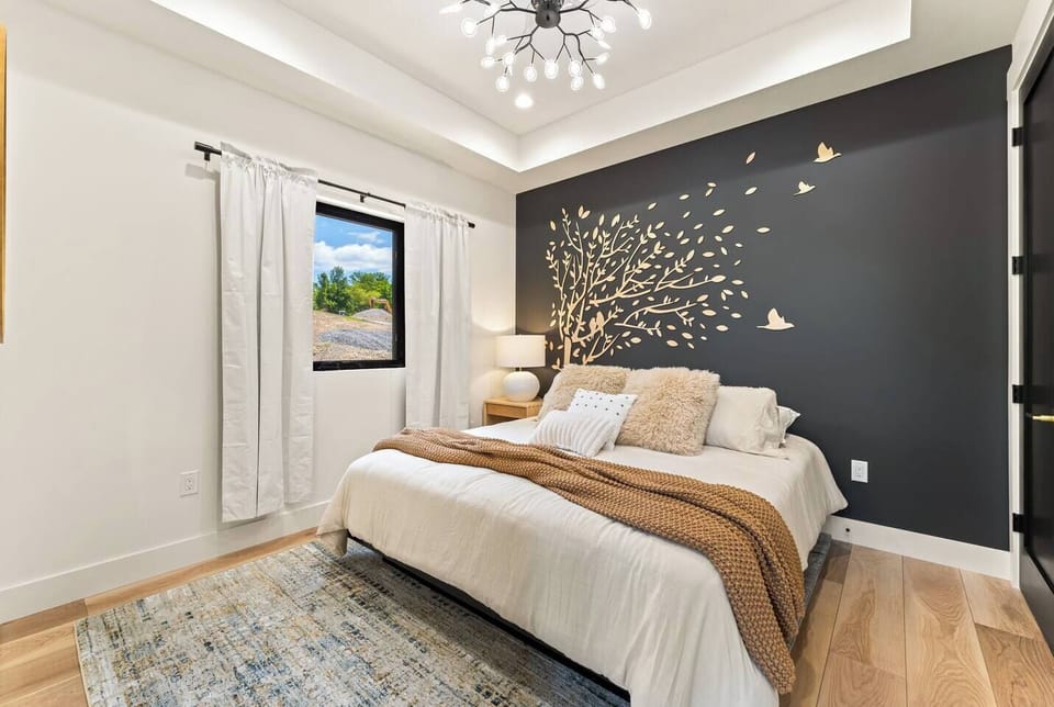 Rest easy in this main-level king bedroom, just steps from the stunning living room. A sculpted tree-and-bird wall feature adds warmth and artistry, creating a peaceful retreat where modern design meets cozy comfort. Room includes a 55" Roku TV.