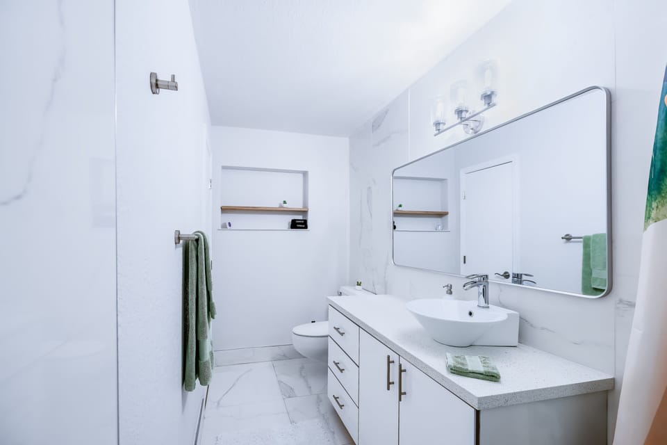 Bright spa-like bathroom with sleek vanity, large mirror, and modern finishes