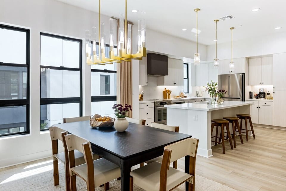 Statement chandelier hangs over the dining table, with the open kitchen and island just steps away.