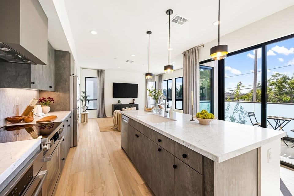 The kitchen island offers plenty of prep space and bar seating, with skyline views just beyond the glass.