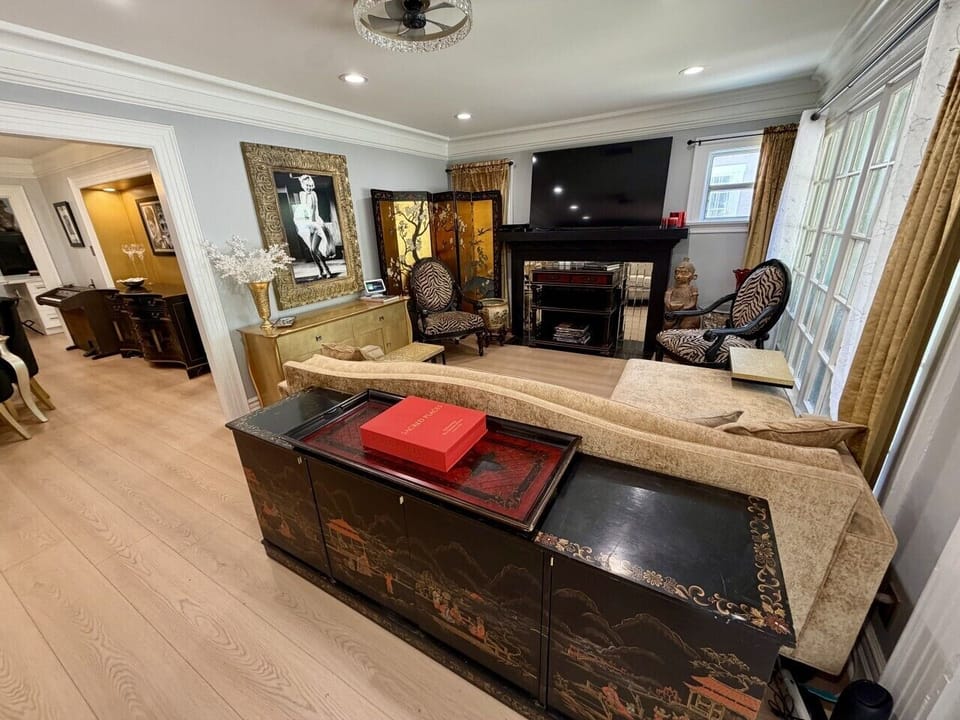 Step into a welcoming living room filled with old Hollywood charm, where elegant chandeliers and museum-scale artwork create a sophisticated yet comfortable atmosphere. This thoughtfully curated space blends timeless character with modern comfort, offerin