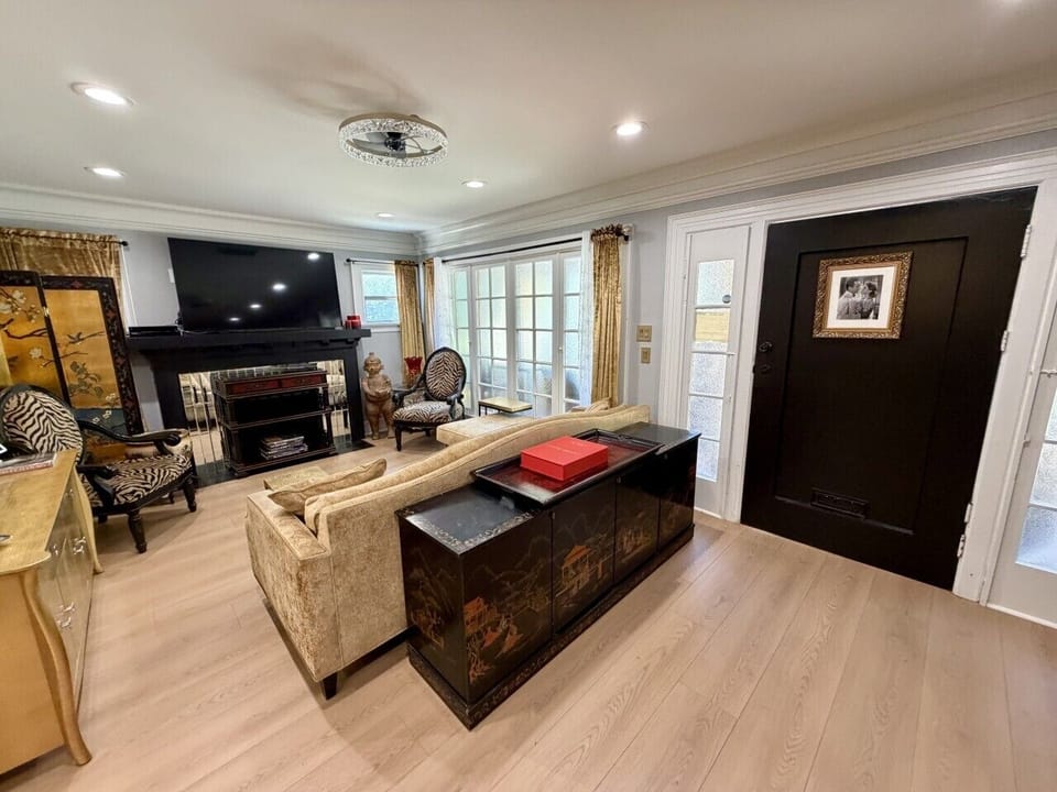 Step into a welcoming living room filled with old Hollywood charm, where elegant chandeliers and museum-scale artwork create a sophisticated yet comfortable atmosphere. This thoughtfully curated space blends timeless character with modern comfort, offerin