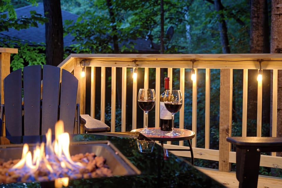Cozy wooded deck with fire table, string lights, and evening wine vibes