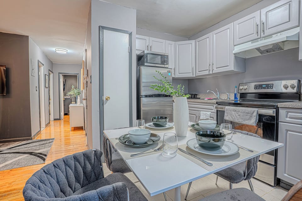 A modern kitchen with white cabinets, stainless steel appliances, and a cozy dining setup.