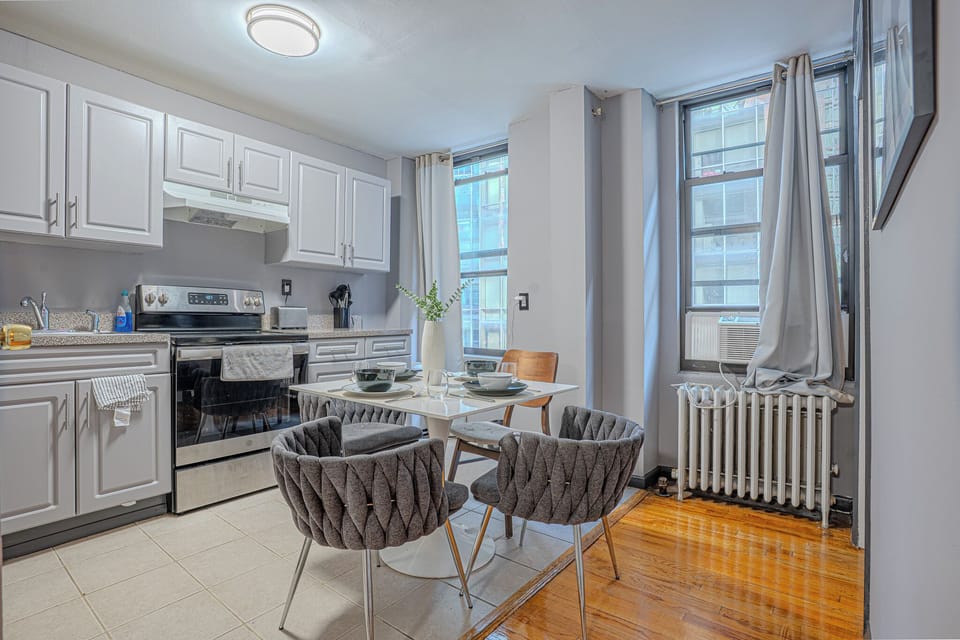 A stylish kitchen with light gray cabinets, a cozy dining setup, and elegant decor.