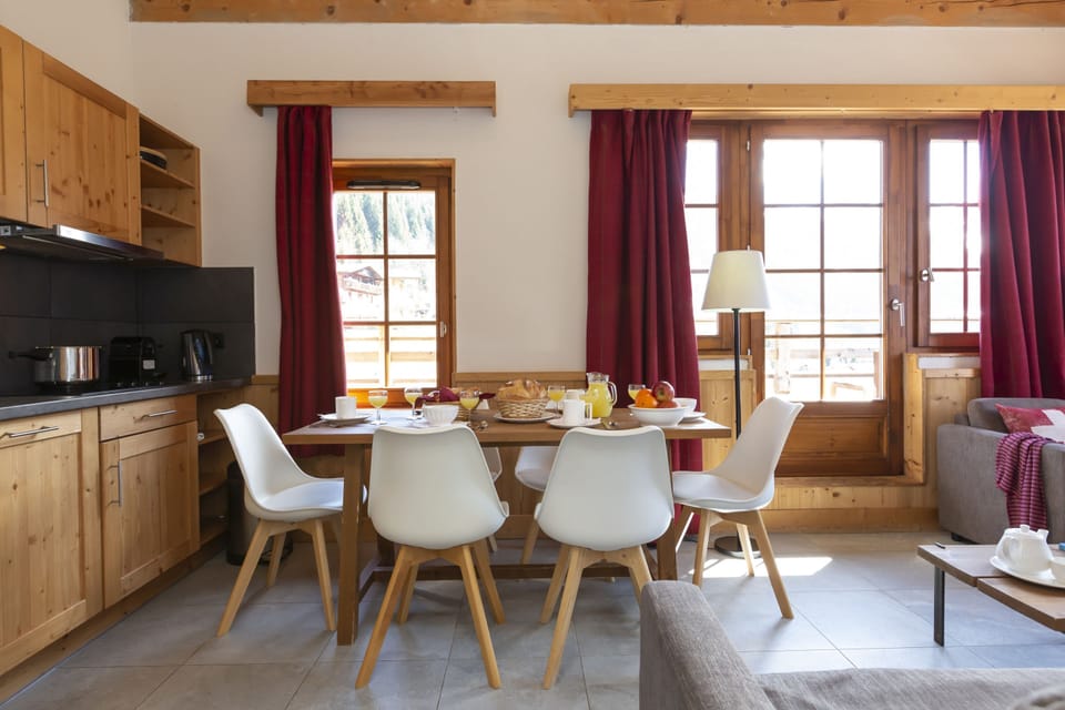 The kitchenette and dining table are set up for easy group meals — perfect for a raclette night in after the slopes.
