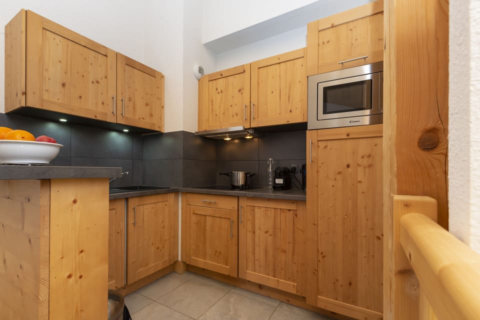 The kitchenette's wooden cabinetry and dark countertops keep everything within reach for group breakfasts before the gondola.
