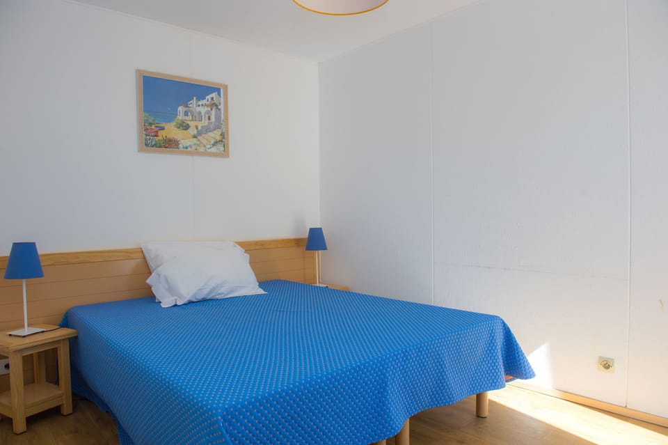 The double bedroom, bright and airy with warm wooden beams and Mediterranean blue tones.