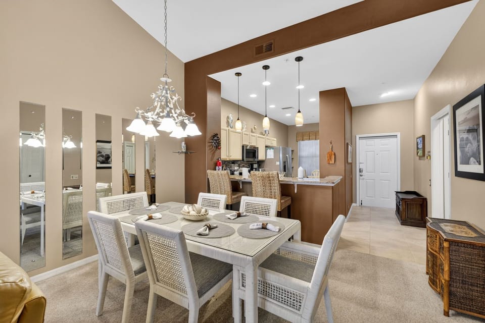 Dining table beneath vaulted ceilings with thoughtful lighting and an open layout seamlessly connecting to the fully-equipped kitchen.