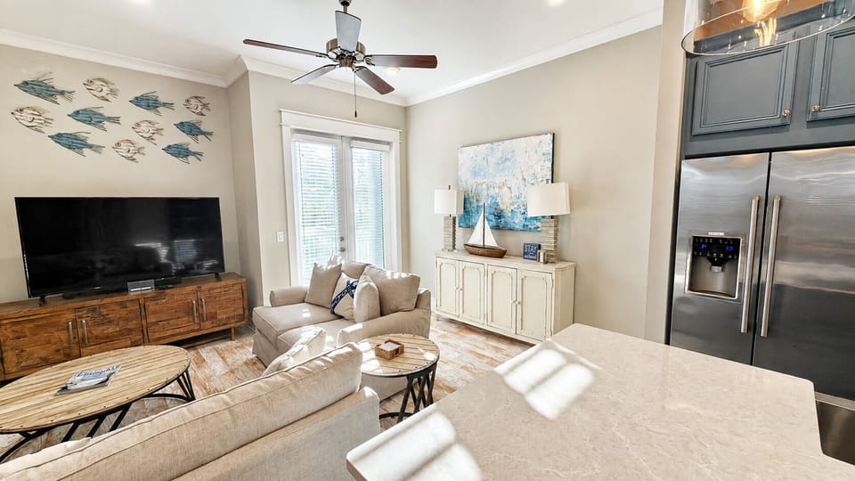 Bright coastal living room with open kitchen, TV, and stylish decor
