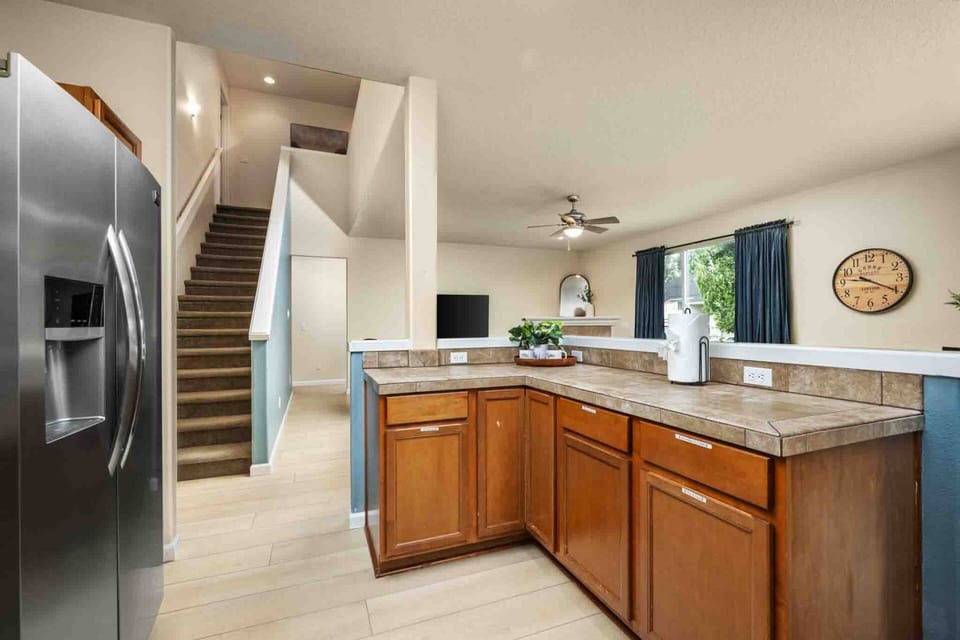 A view looking from behind the kitchen counter toward the staircase, entry hall, and main living area.
