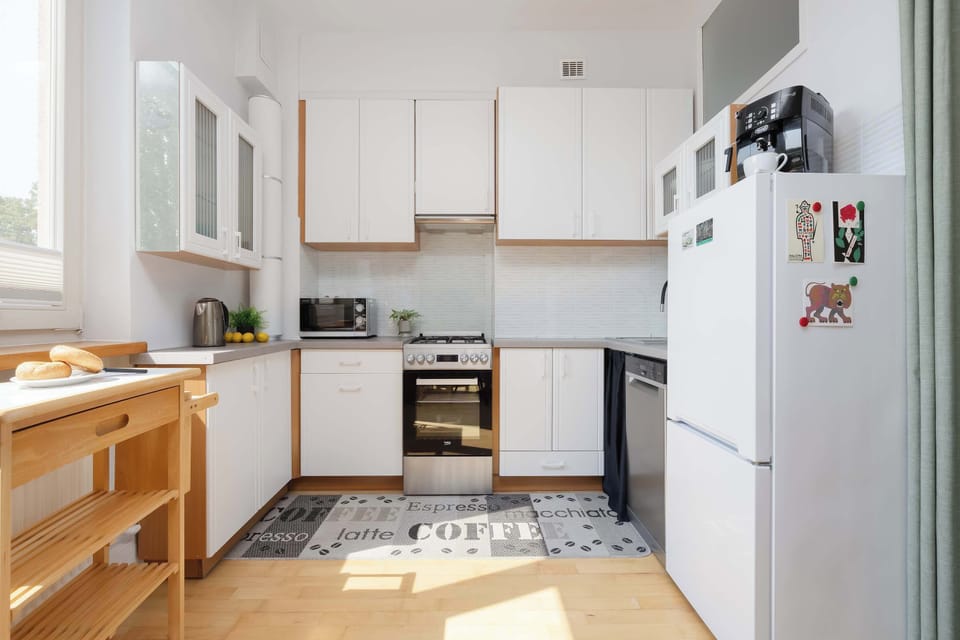 A functional kitchen features white cabinetry, wooden countertops, and modern appliances arranged along two walls. The compact layout provides everything needed for everyday cooking.