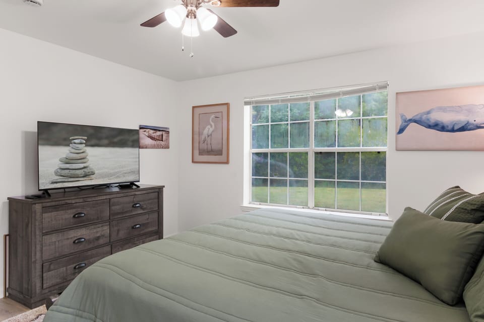 Smart TV, cozy linens, and coastal art set the tone for a relaxing stay