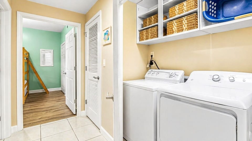 Your laundry room is bright and fully equipped with a washer and dryer, plus overhead shelving with baskets to keep your beach gear organized and ready for your next adventure.