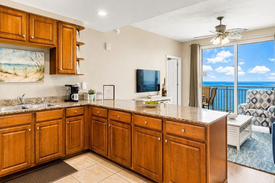 Wake up to stunning ocean views from your open-plan kitchen and living space. The warm wood cabinets, granite countertops, and breezy balcony create your perfect seaside escape.