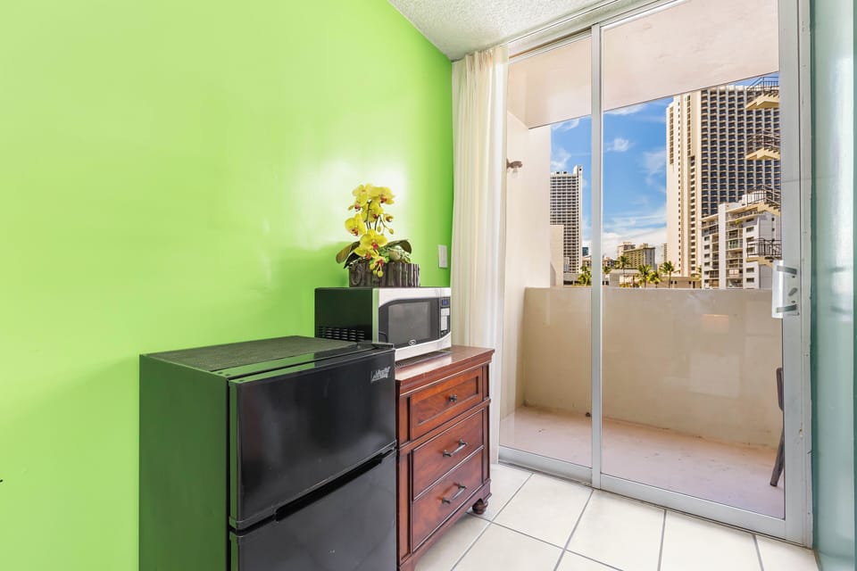 Your cozy kitchenette offers a mini-fridge, microwave, and private balcony where you can savor morning coffee with vibrant city views framed by towering high-rises.