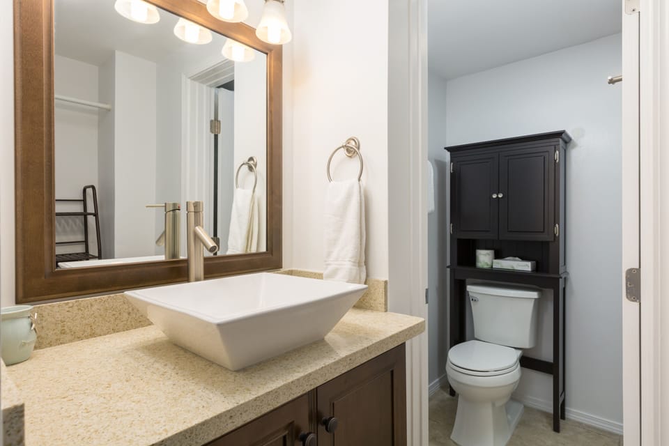 Your private bathroom features a modern vessel sink, warm wood accents, and ample storage—everything you need to feel refreshed and at home.