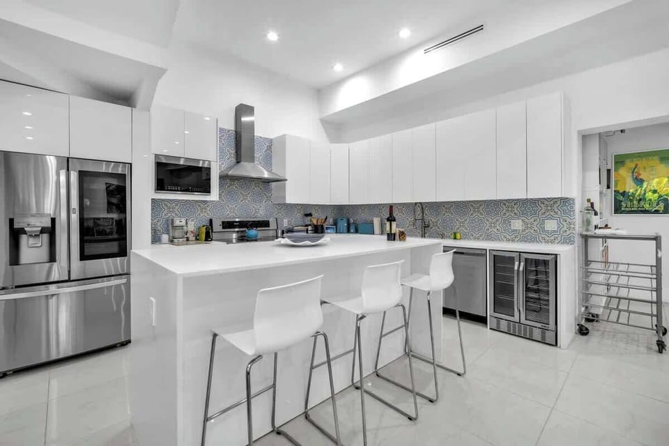 Sleek, fully equipped kitchen featuring a spacious center island with bar seating for four, stainless steel appliances, and a built-in wine cooler