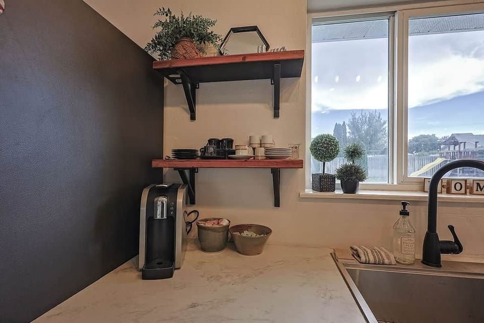 Coffee station with open shelving, décor, and backyard views from the sink