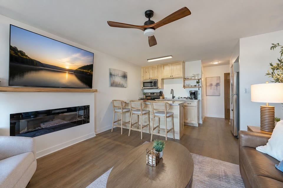 Bright open-concept living space with a fireplace, full kitchen, and seating for gathering together.