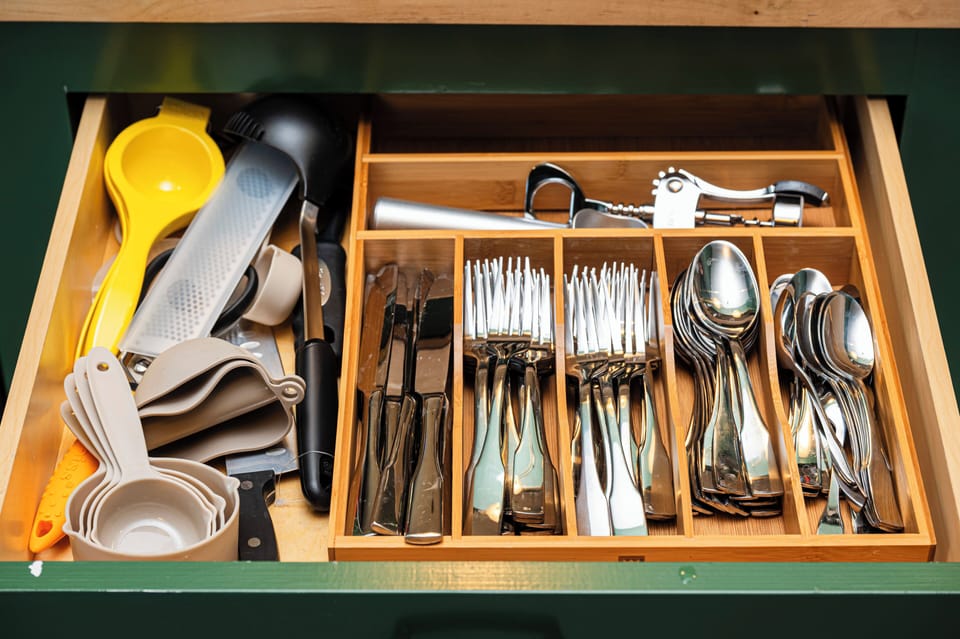 Well-equipped drawer with organized cutlery, tools, and measuring cups.