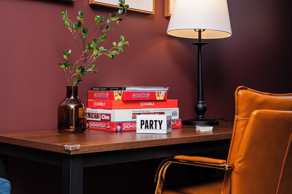 Cozy game nook with classic board games, leather chair, and warm lighting.