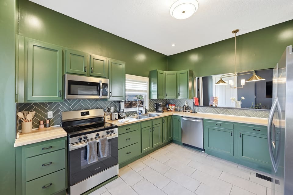 Stylish green kitchen w/ gas range, SS appliances & herringbone tile