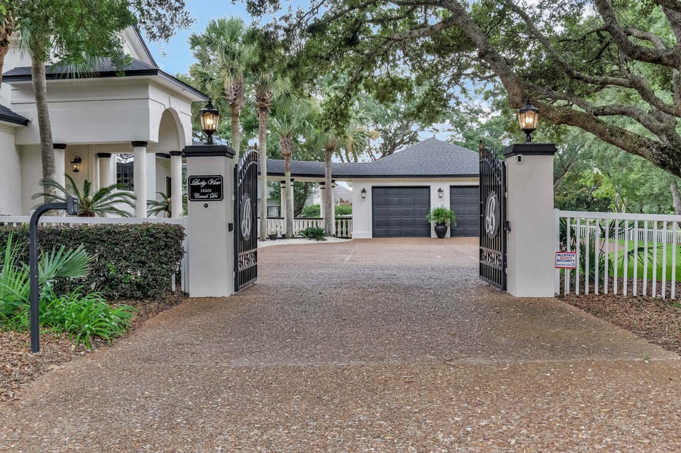 A gated entrance with a paver driveway and tropical landscaping greets arriving guests with a private, secure feel. It's the entry point to one of Innerarity Point's more exclusive waterfront vacation rentals.
